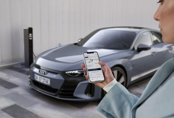 Voorgrond: Een vrouw controleert het verbruiks- en kostenoverzicht voor de Audi e-tron Charging Service in haar myAudi app.
Achtergrond: Een Audi e-tron GT laadt op bij een openbare laadpaal